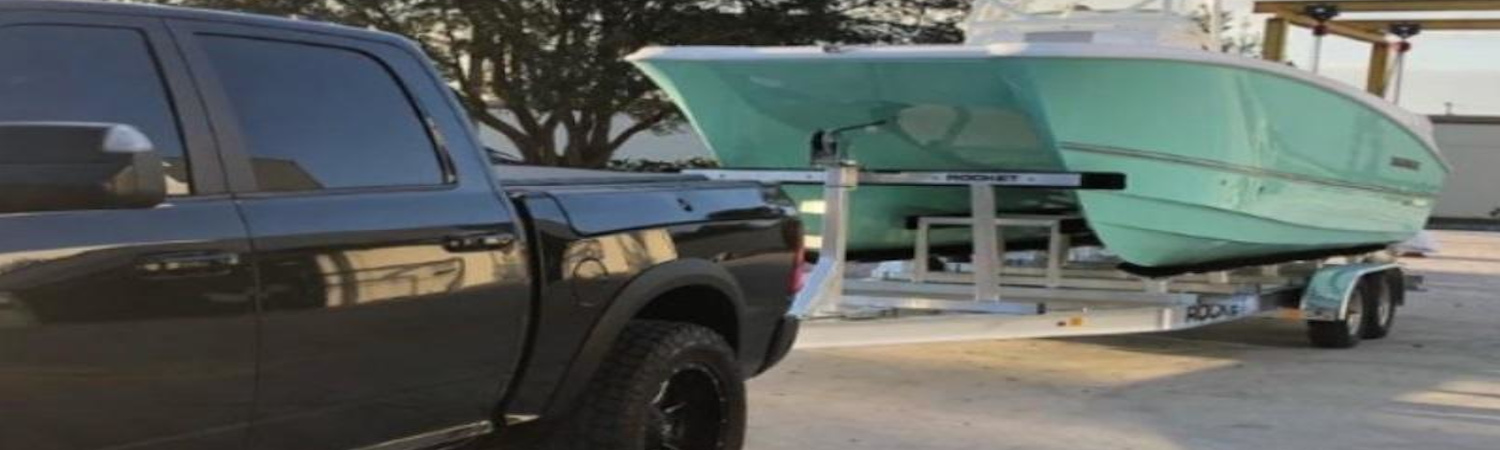 A black pickup truck that's towing a Rocket trailer carrying a boat