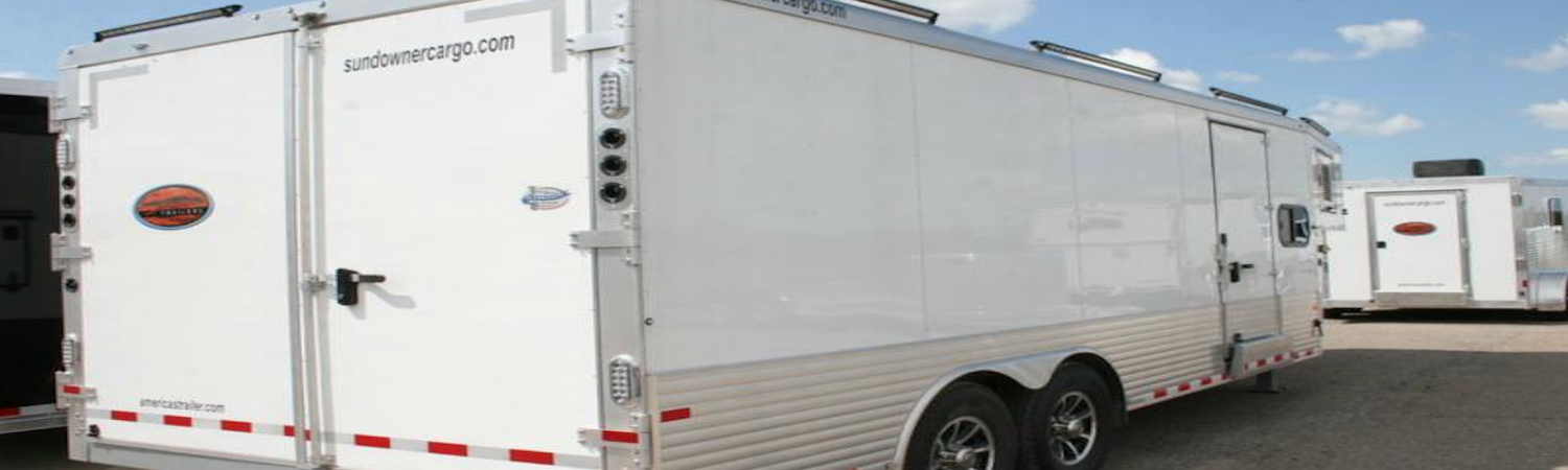 The back of a Sundowner trailer that's parked in a lot with other Sundowner trailers